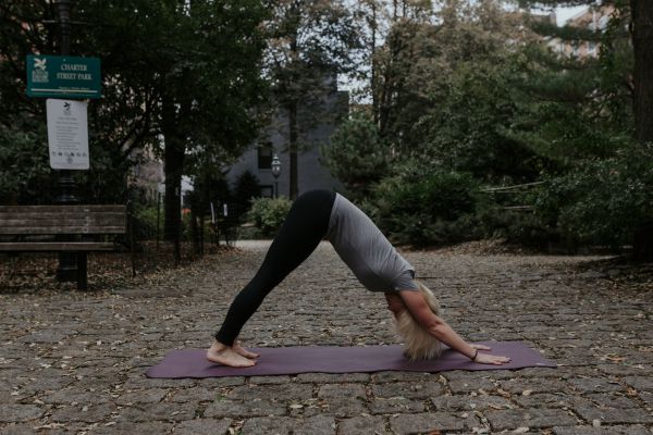 Woman doing yoga outside downward facing dog pose | 11 Beginner-Approved Yoga Exercises to Boost Your Day