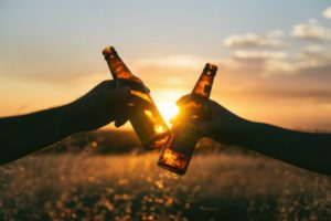 two beer bottles toasting over sunset | How to Make Fitness a Habit That Actually Sticks