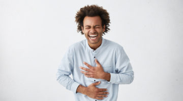 black man laughing holding stomach | How to Increase Happiness With Science-Backed Strategies