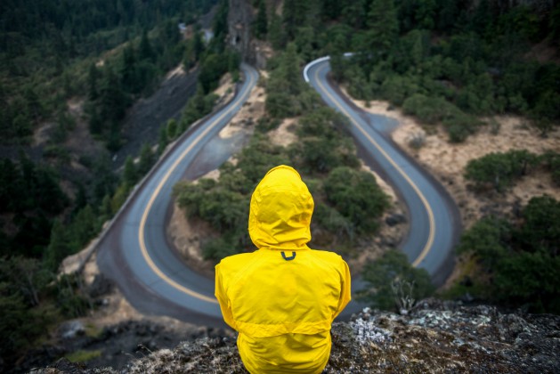Man in yellow raincoat looking over winding road | What Are Daily Habits and How to Build Better Ones