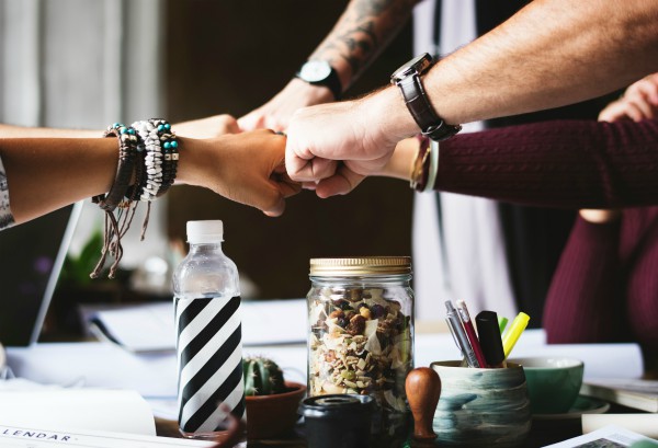coworkers joining fists teamwork | What Productivity Means and How to Get Better at It