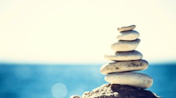 stacked rocks near ocean | What is Wellness and How to Make It Work for You https://positiveroutines.com/wellness-definition/