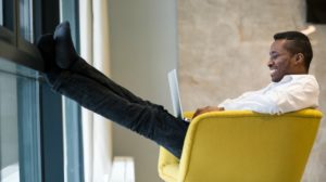 black man leaning back in yellow chair smiling | These Mindfulness Meditation Exercises Will Change Your Day