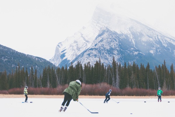 four people playing hockey outside against mountain | Have a Happy Holiday by Sticking to Your Fitness Routine