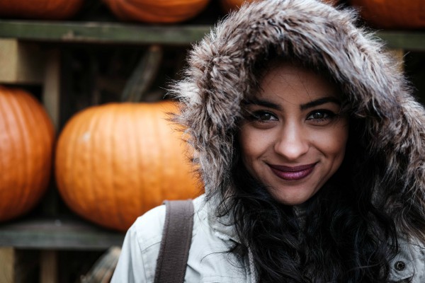indian woman smiling with furry hood | Got Holiday Stress? This Expert-Backed Tip Can Help