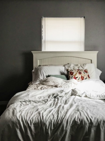bed with gray and white sheets against gray wall | Make Good Mornings: How to Master Your A.M. Routine https://positiveroutines.com/tips-for-good-mornings/