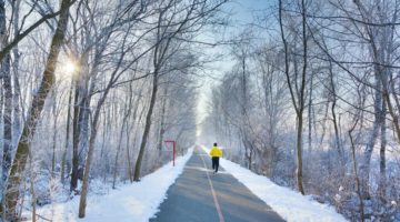 man running down path in snowy woods | Have a Happy Holiday by Sticking to Your Fitness Routine