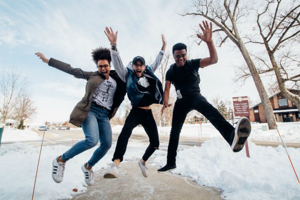 three diverse friends jumping against snowy background | The Science of Happiness: How to Focus on Friendship