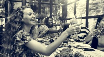 happy women around table toasting | 3 Habits of Happy People You Should Borrow