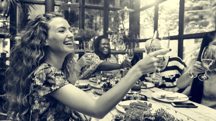 happy women around table toasting | 3 Habits of Happy People You Should Borrow