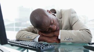 black man in suit asleep at work | Why Sleep is Key to Increasing Productivity