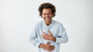 black man laughing holding stomach | 54 Ways to Be Happy That Will Crush the Winter Blues