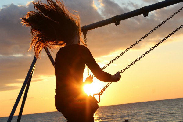 girl swinging at sunset over ocean | 54 Ways to Be Happy That Will Reverse the Winter Blues https://positiveroutines.com/ways-to-be-happy/ ‎