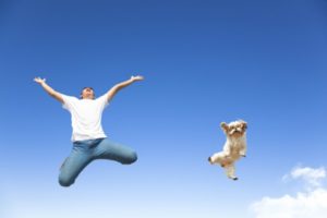 man and dog jumping in air | 54 Ways to Be Happy That Will Crush the Winter Blues