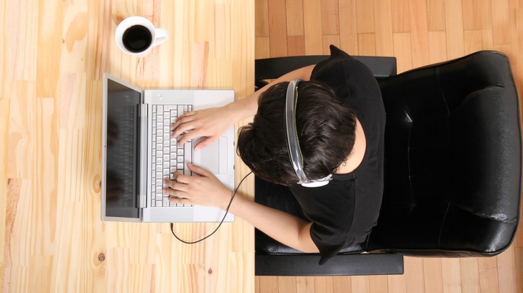 top view of productive man working on laptop wearing headphones| 48 Podcasts Guaranteed to Change Your Life https://positiveroutines.com/influential-podcasts