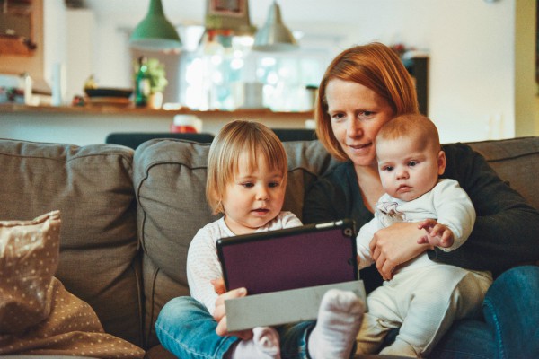 woman with two babies looking at tablet | Simple Acts of Kindness to Try This Valentine's Day