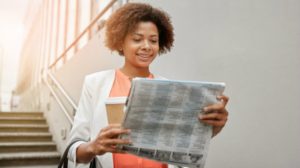 black woman holding coffee reading newspaper | 7 Successful Women Share: My Best Morning Routine