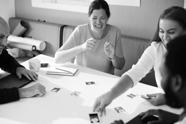 black and white image of four people collaborating happily | How to Be More Positive at Work, According to Science