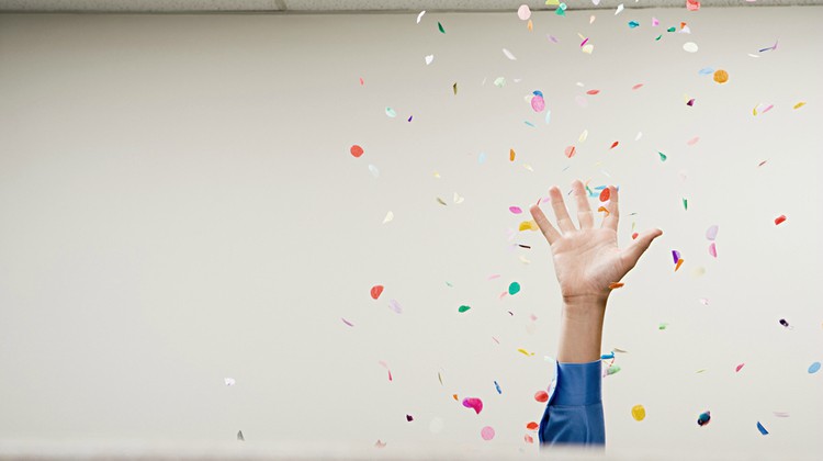 businessman hand in office throwing confetti | How to Be More Positive at Work