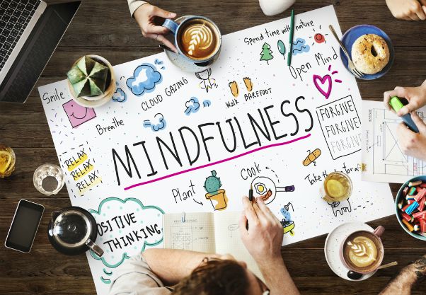 colorful graphic of mindfulness sign on table with people and coffee | 26 Ways to Make Practicing Mindfulness Part of Your Day