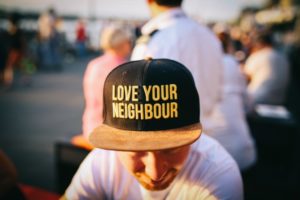 man wearing hat that says love your neighbor | The Research-Backed to Money and Happiness