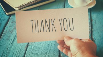 mans hand holding thank you note | 10 Expert-Approved Gratitude Messages for Mom