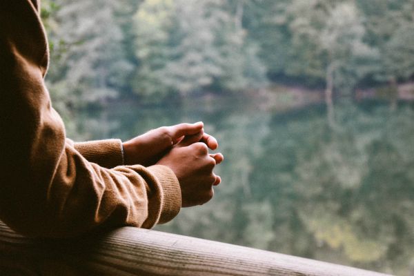 mans hands over railing in the woods thinking | Feeling Work Stress? 1 Surprising Way to Get Relief https://positiveroutines.com/work-stress-relief/