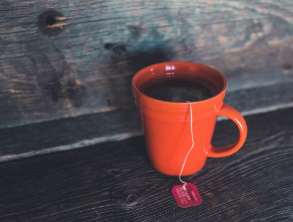 red cup of tea on wooden table | An Adult Bedtime Routine for the Best Sleep Ever https://positiveroutines.com/bedtime-routine-for-adults/