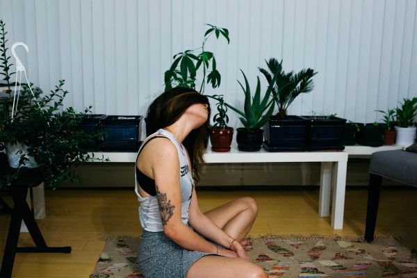 woman doing yoga in her living room with plants | The Best Hip Exercises for People Who Sit All Day https://positiveroutines.com/best-hip-exercises/