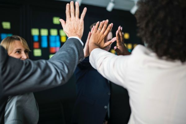 business people giving each other high fives | Can Staying Positive Increase Your Productivity? https://positiveroutines.com/staying-positive-increase-productivity/