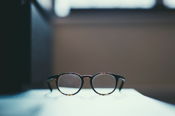 glasses on table in focus | What are SMART Goals + How Do You Set Them? https://positiveroutines.com/what-are-smart-goals/