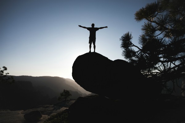 man on boulder in desert with arms outstretched | What are SMART Goals Really + How Do You Set Them? https://positiveroutines.com/what-are-smart-goals/