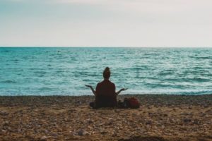 silhouette of woman meditating by the ocean | Looking for a Meditation Podcast? Here Are Our Top 10 https://positiveroutines.com/best-meditation-podcast/
