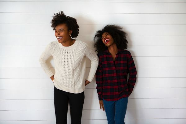 two black women standing against a wall laughing | 3 Expert Secrets to Relationship Building https://positiveroutines.com/relationship-building-secrets/