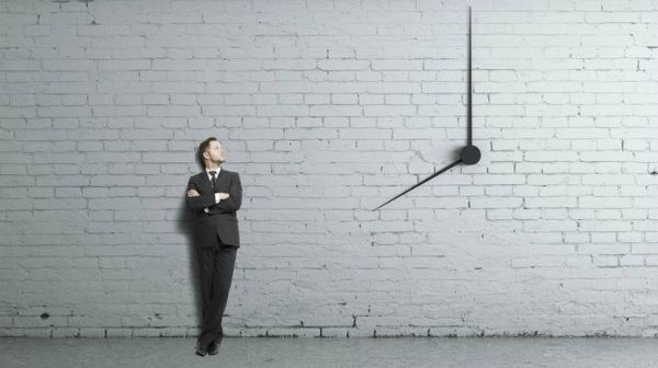 businessman standing near clock on wall time management concept | 75 Great Apps That Will Change Your Life https://positiveroutines.com/great-apps-for-change/ 