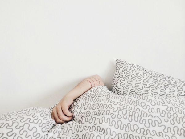 gray duvet covering person with one arm showing | Can Caffeine Help You Do Something Productive? https://positiveroutines.com/do-something-productive/