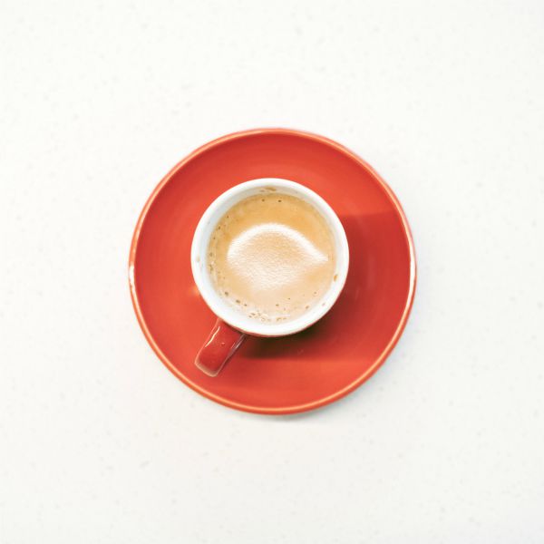 overhead shot of coffee cup on red saucer | Can Caffeine Help You Do Something Productive? https://positiveroutines.com/do-something-productive/