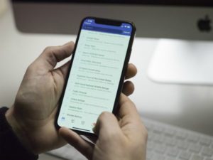 person holding phone looking at list | Can a Productivity App Teach You How to Be More Organized? https://positiveroutines.com/how-to-be-more-organized-app/