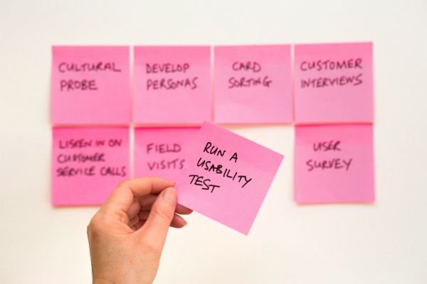 pink post it notes on wall with hand holding one for usability test | The Best Time-Management Apps for Better Work-Life Balance https://positiveroutines.com/best-time-management-apps/ 