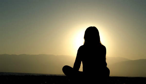 silhouette of woman at sunset sitting cross legged | Why You Need to Try Loving-Kindness Meditation https://positiveroutines.com/loving-kindness-meditation/