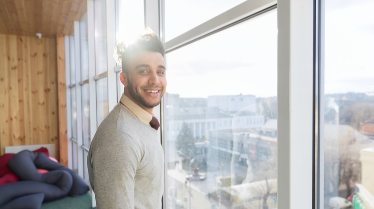sunlight hitting latino business man standing in front of window | Increase Productivity at Work in This Simple Way  https://positiveroutines.com/increase-productivity-at-work/ 