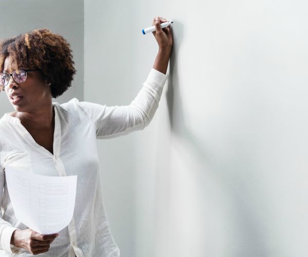 black woman writing on white board | One of the Best Benefits of Napping? Increased Productivity https://positiveroutines.com/productivity-benefits-of-napping/