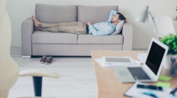 businessman napping on couch with work nearby | One of the Best Benefits of Napping? Increased Productivity https://positiveroutines.com/productivity-benefits-of-napping/