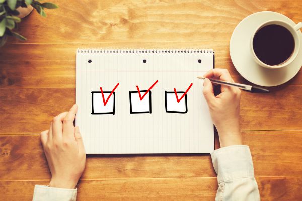 checklist on table with three red checks | 59 Work Tips to Be Better At Your Job  https://positiveroutines.com/best-work-tips/