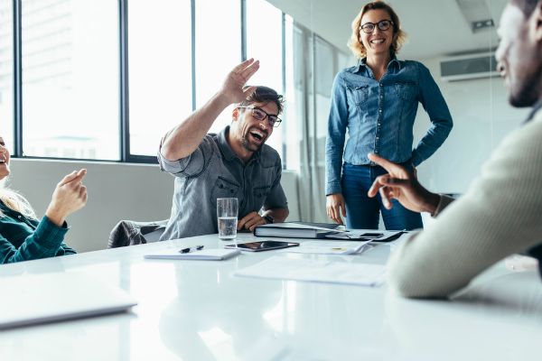 coworkers in conference room giving high fives | 59 Work Tips to Be Better At Your Job  https://positiveroutines.com/best-work-tips/