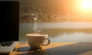 cup of coffee and laptop overlooking water | This Is the Morning Routine That Will Make You Successful