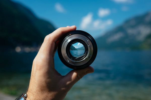 hand holding camera lens over landscape focus concept | This Is the Morning Routine That Will Make You Successful