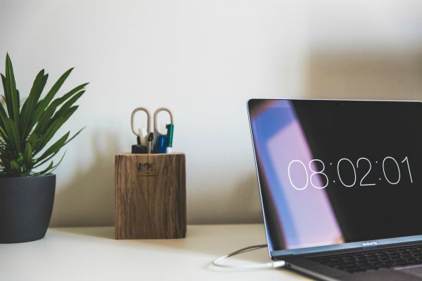 mac laptop displaying time on white desk | 5 Surprising Habits of Super Productive People