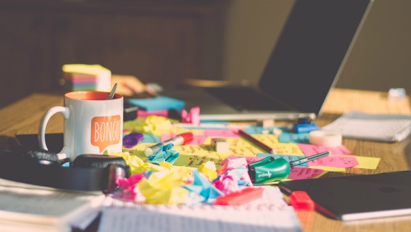 messy desktop with colorful paper | The Best Decluttering Tips for a Productive Workspace https://positiveroutines.com/decluttering-tips/