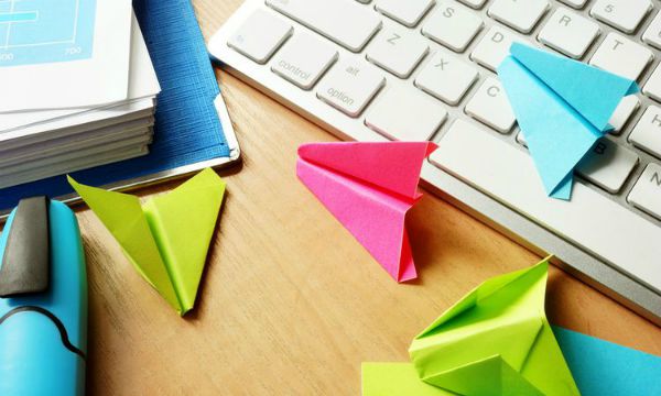 procrastination concept paper airplanes from post its near keyboard | 59 Work Tips to Be Better At Your Job  https://positiveroutines.com/best-work-tips/